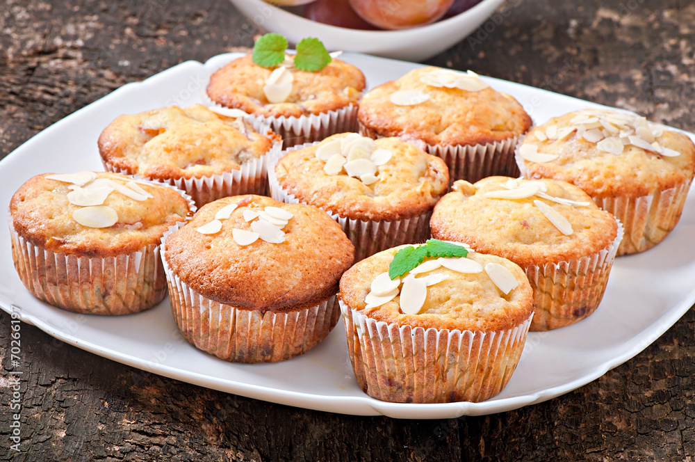 Muffins with plums and almond petals decorated with mint leaves Muffins with plums and almond petals decorated with mint leaves