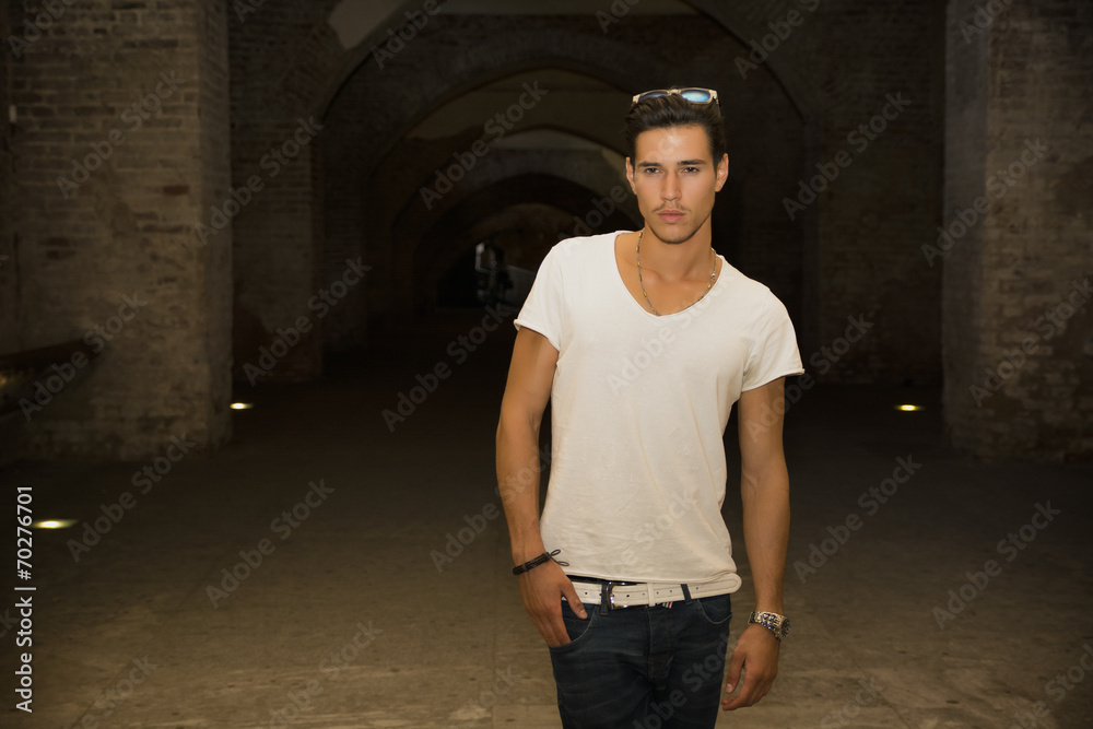 Handsome young man in old building walking inside gallery