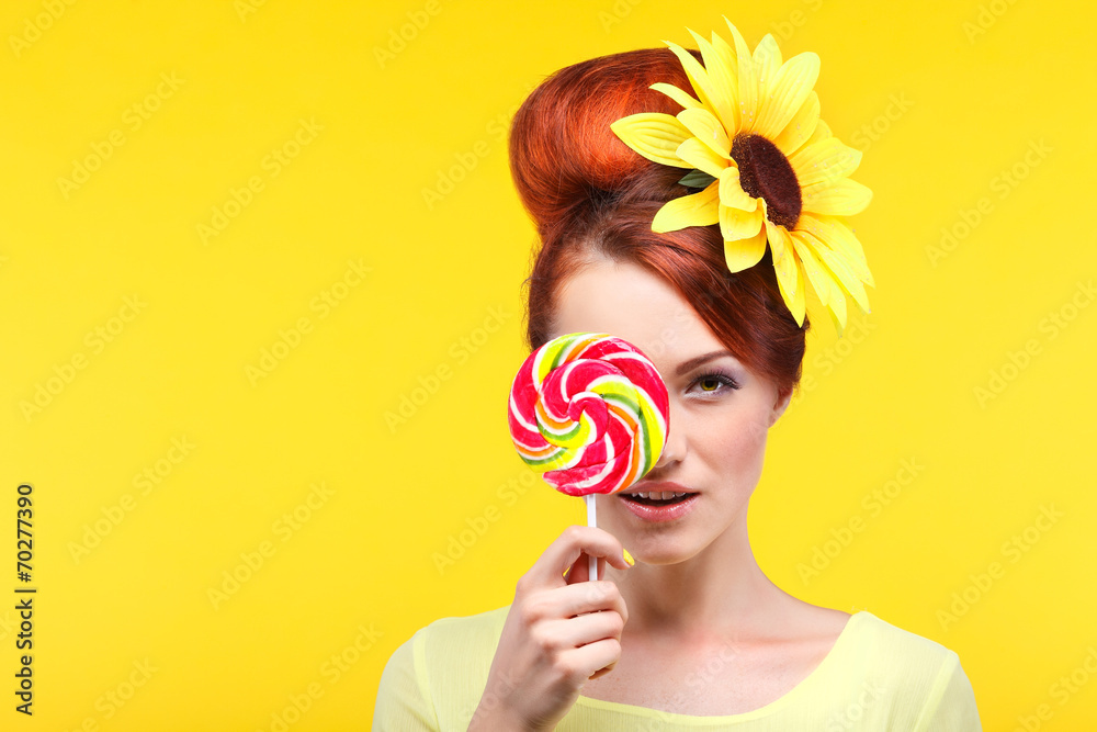 Beautiful girl with a large candy on a yellow 