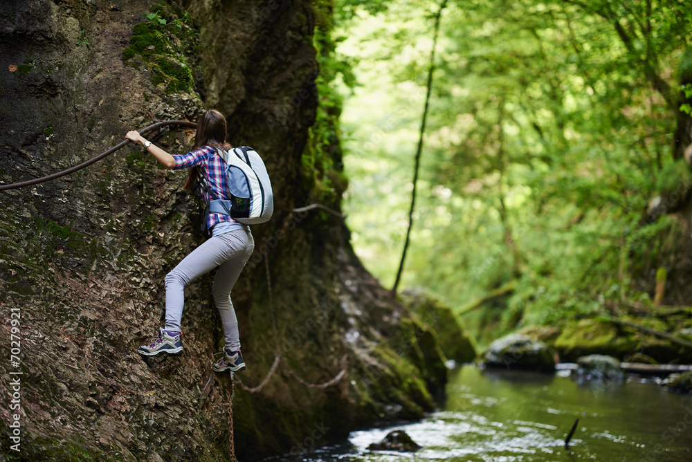 Lady climber on safety cables over river Lady climber on safety cables over river