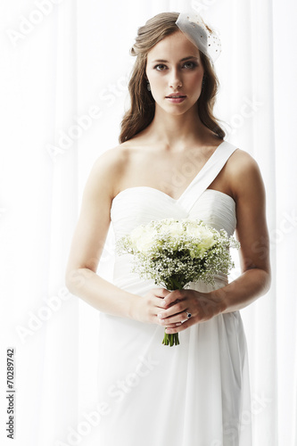 Young bride in wedding dress holding bouquet, portrait .