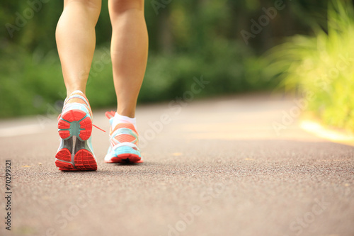 young fitness woman legs running at forest trail 