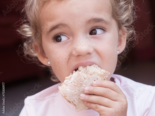 Little girl eating a piece of bread