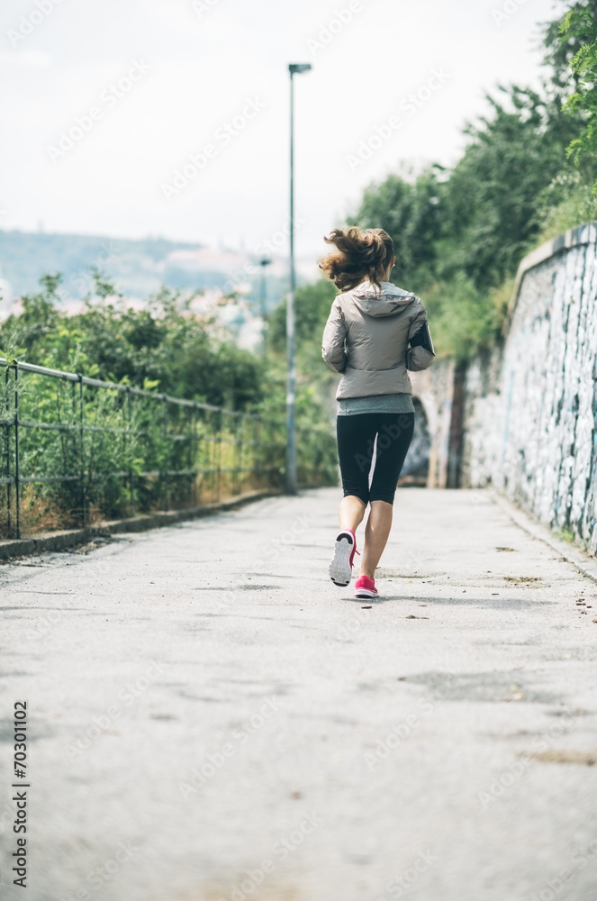 Fitness young woman jogging in the city park