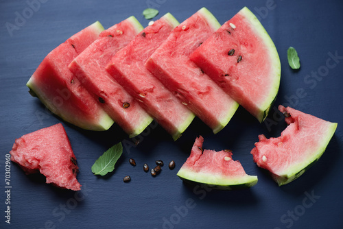 Sliced watermelon over dark blue wooden surface, studio shot