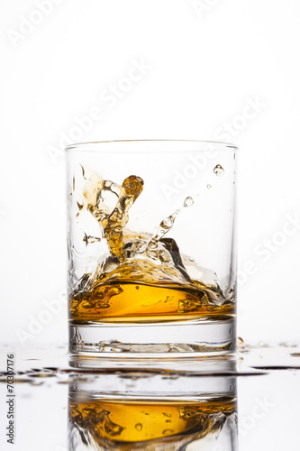 Whisky splashing in glass on a white background