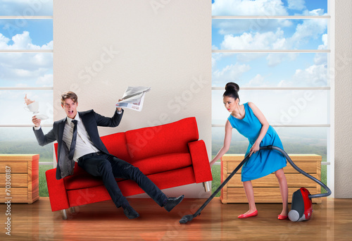 Angry woman vacuuming while man is resting photo