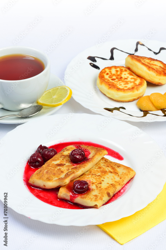 Food of Crepes, cheesecakes with berry sause and cup of tee. Food of Crepes, cheesecakes with berry sause and cup of tee.