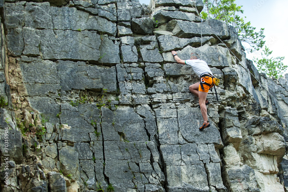 Climber climbing on top of a mountain with a safety rope Climber climbing on top of a mountain with a safety rope
