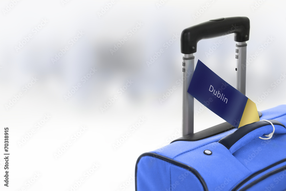 Dublin. Blue suitcase with label at airport. StockFoto Adobe Stock