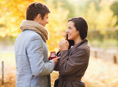 smiling couple with red gift box in autumn park