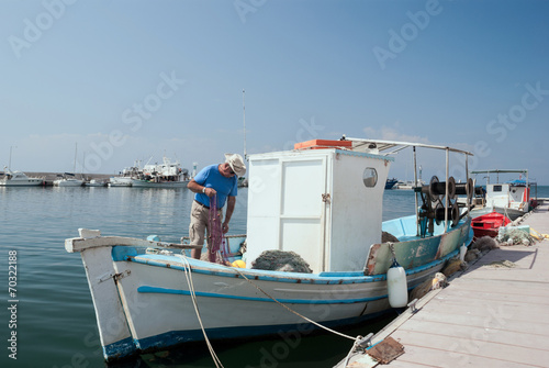 Adult fisherman on white traditional boat in Greece