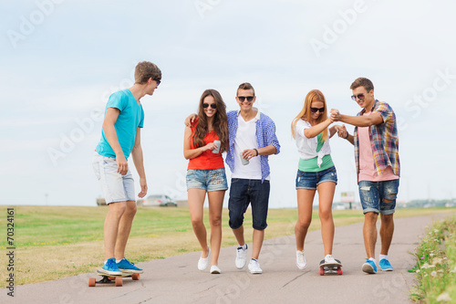 group of smiling teenagers with skateboards