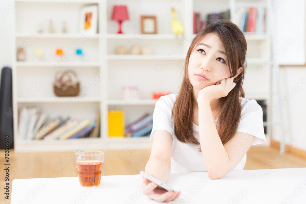 部屋でスマートフォンを見る女性 部屋でスマートフォンを見る女性