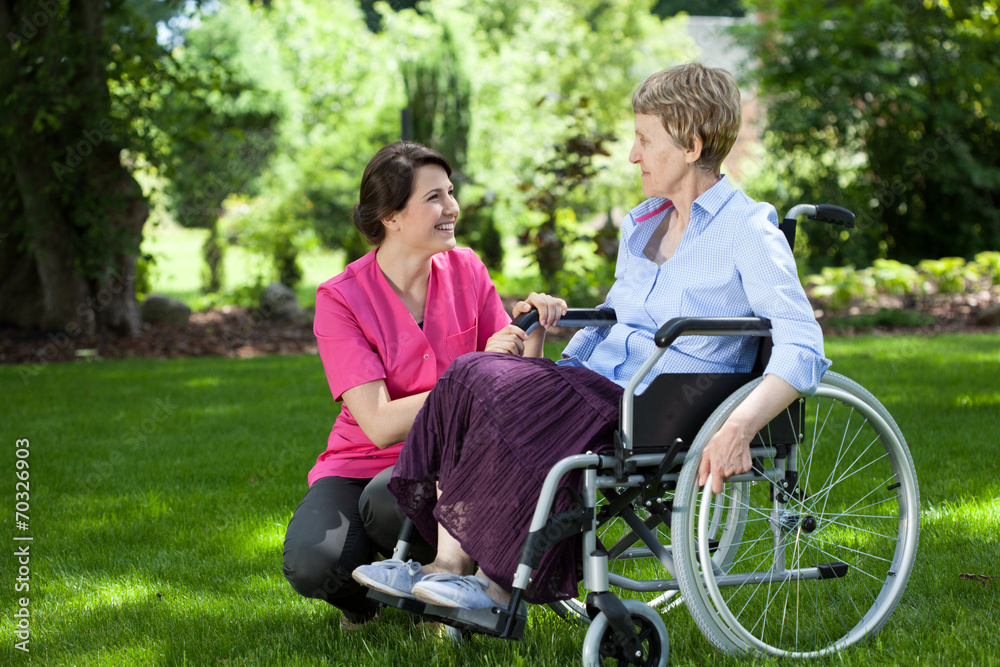 Senior woman on wheelchair with caring caregiver Senior woman on wheelchair with caring caregiver