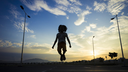 Silhouette girl jumping at open area with sunrise background