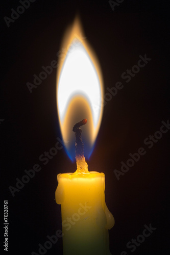 Burning candle on the black background