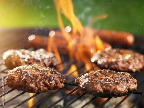 Vászonkép hamburgers and hotdogs cooking on flaming grill