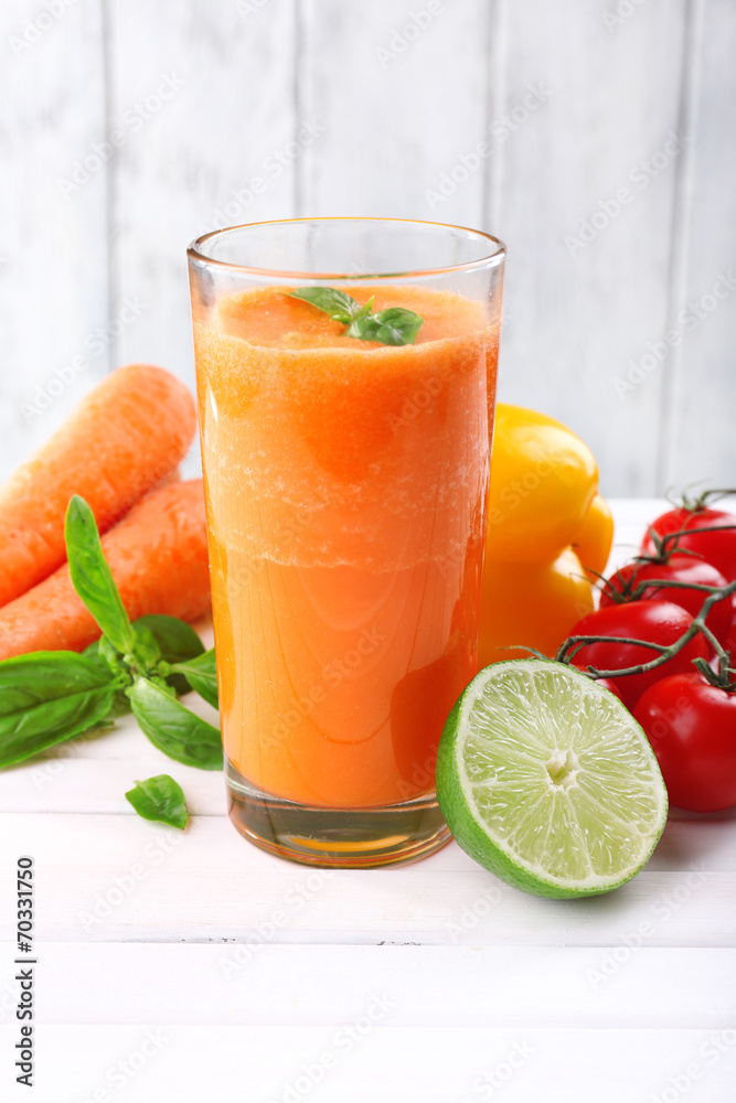 Glass of fresh carrot juice and vegetables on wooden table Glass of fresh carrot juice and vegetables on wooden table
