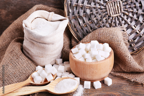 Refined sugar in bag and bowl on wooden background