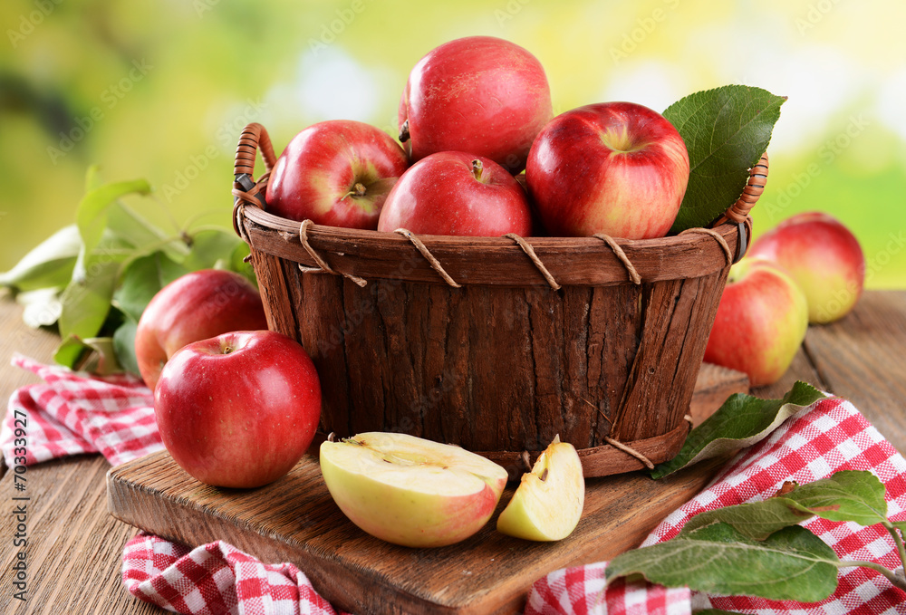 Sweet apples in wooden basket on table on bright background Sweet apples in wooden basket on table on bright background