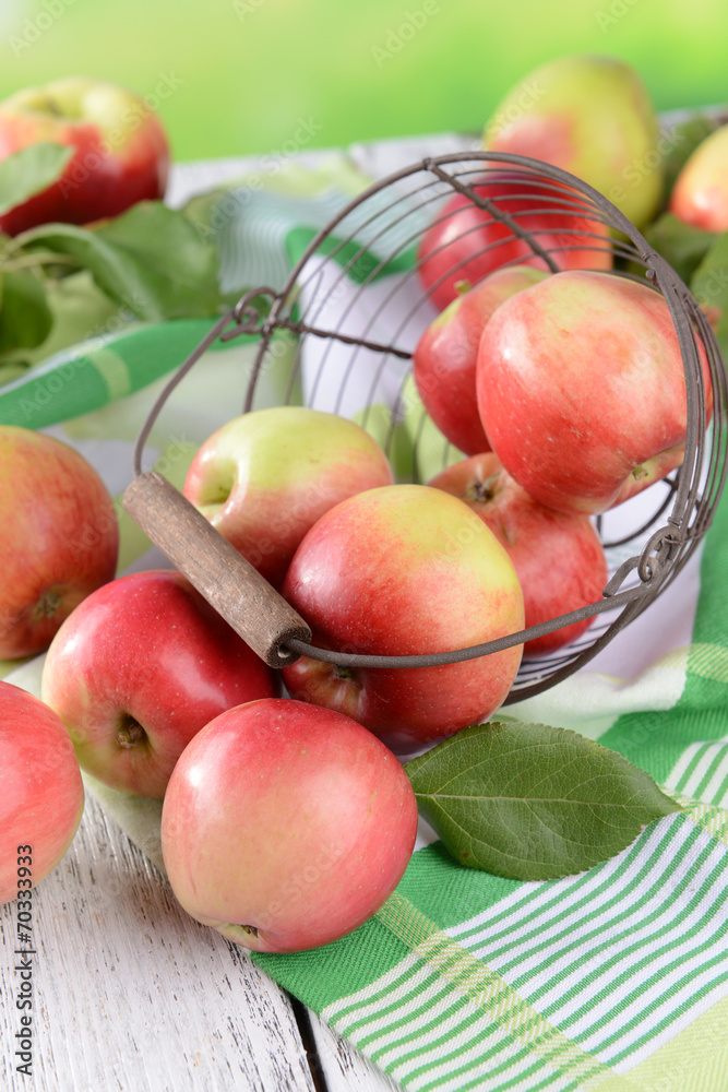 Sweet apples in wicker basket on table on bright background Sweet apples in wicker basket on table on bright background