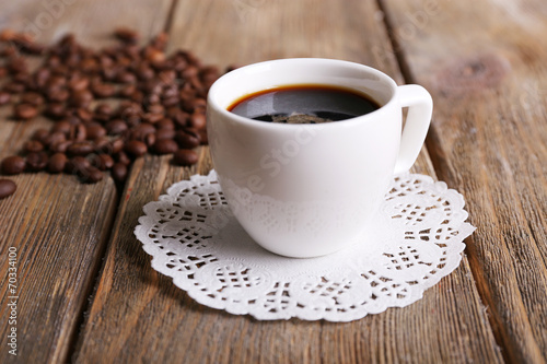 Cup of coffee and coffee beans on napkin on wooden background