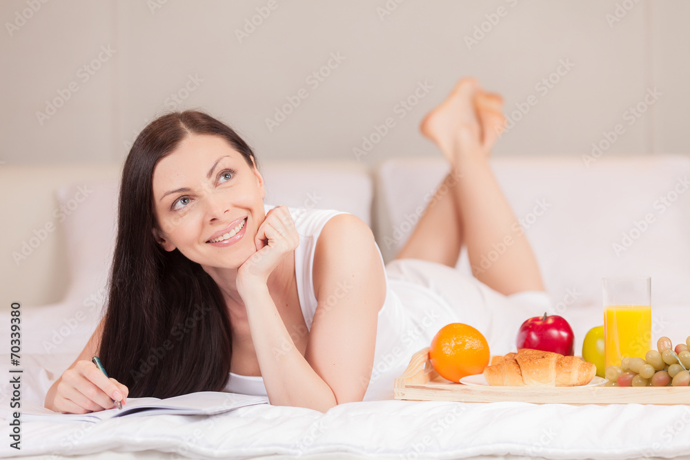Girl writes having breakfast in bed in morning. Girl writes having breakfast in bed in morning.