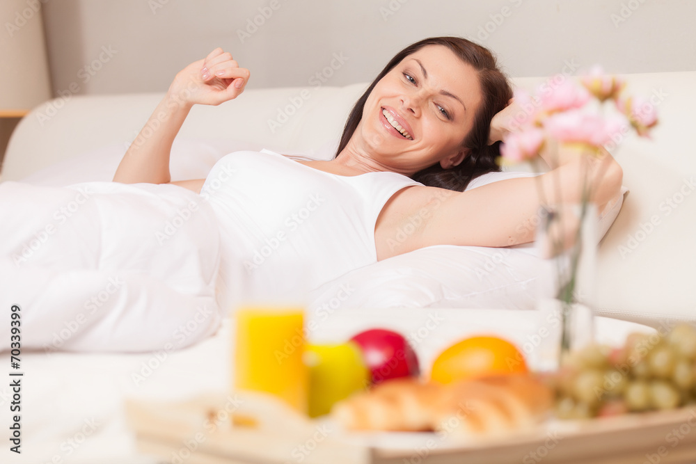 Happy woman stretching in bed in the morning.