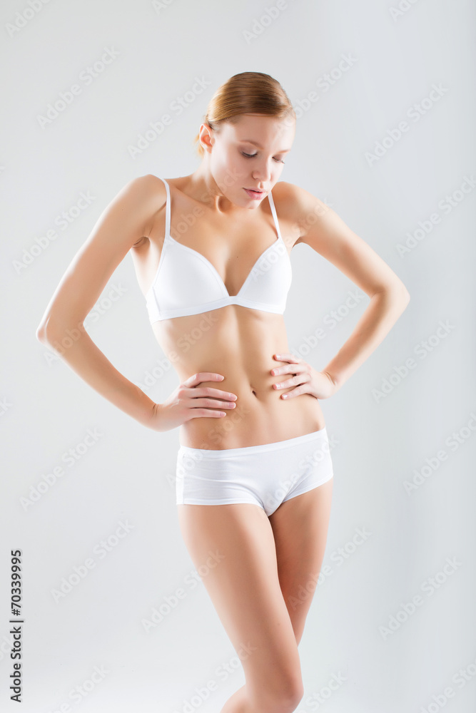 Obraz premium Young woman with beautiful slim perfect body in bikini isolated