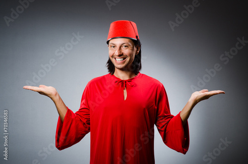 Man in red dress wearing fez hat photo