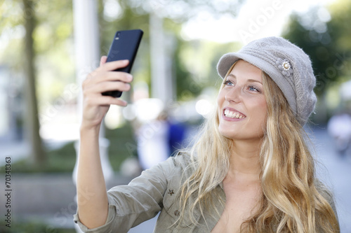 Trendy girl with hat taking picture with smartphone