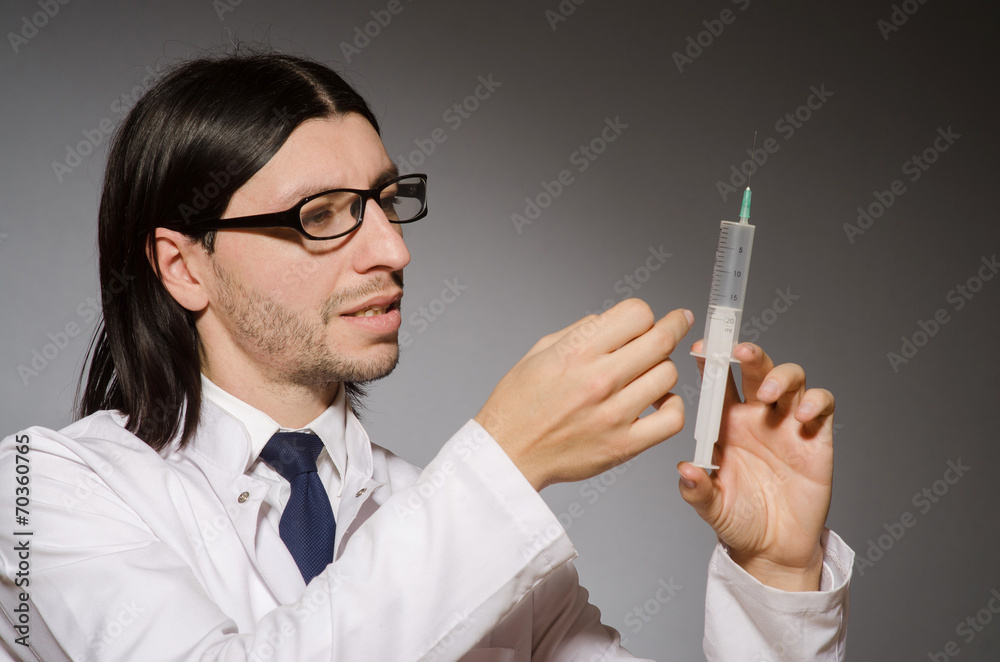 Young doctor man with syringe against grey background Young doctor man with syringe against grey background