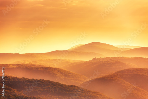 View of a valley in a beautiful early morning with fog between h