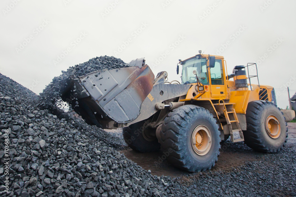 Yellow heavy excavator and bulldozer unloading road metal during Yellow heavy excavator and bulldozer unloading road metal during