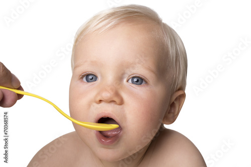 One year old boy eating with spoon