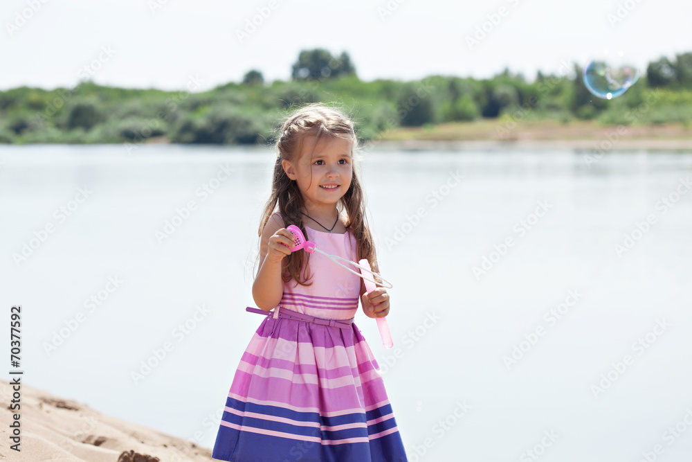 Beautiful little girl blowing soap bubbles in park Beautiful little girl blowing soap bubbles in park