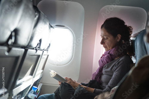 Woman reading book inside airplane.