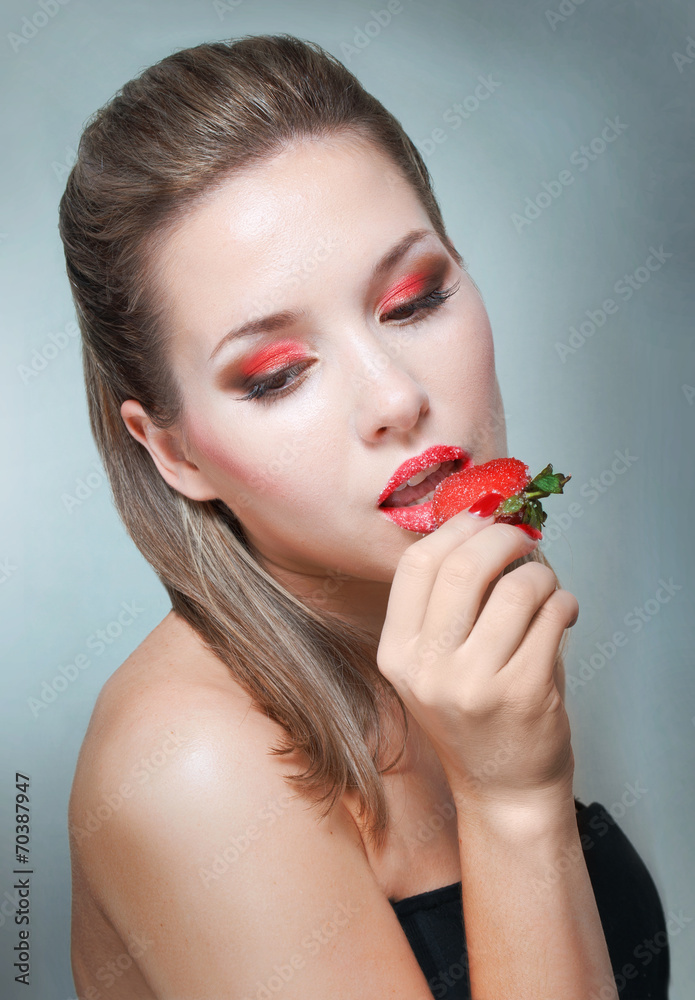 Studio portrait of young woman with strawberry Studio portrait of young woman with strawberry