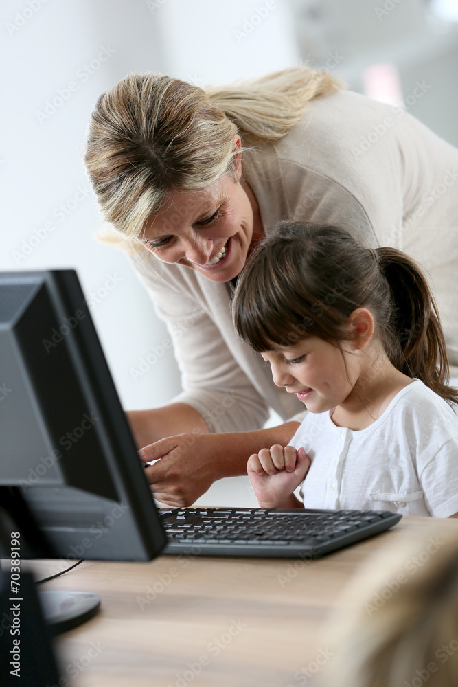 Teacher with little girl in class using computer and tablet Teacher with little girl in class using computer and tablet