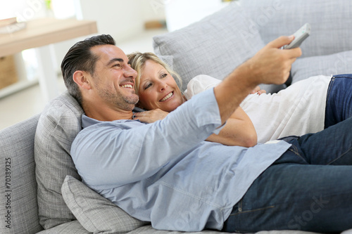 Middle-aged couple in sofa watching tv