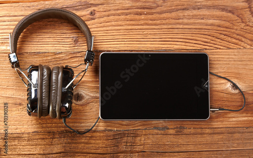 Tablet with headphones on old wooden desk. photo