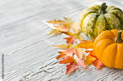 Pumpkins on wooden background with autumn leaves