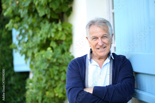 Senior man leaning on wall outside the house photo