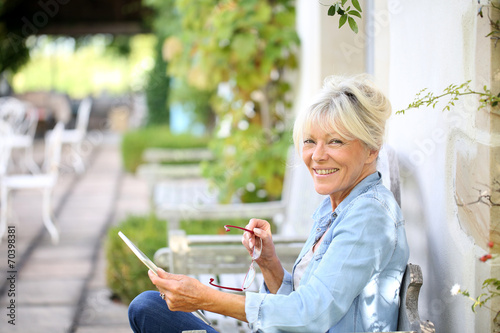 Senior woman relaxing outside and using tablet