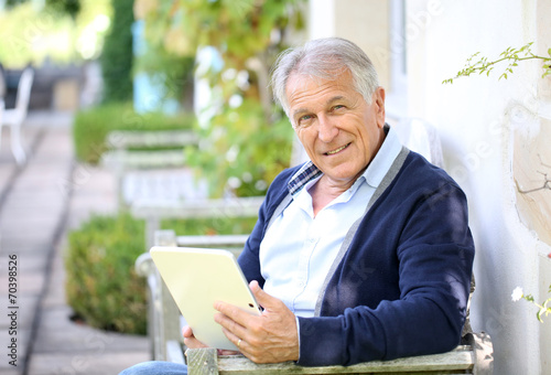 Senior man websurfing on tablet outside the house