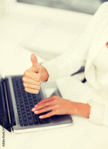businesswoman with laptop showing thumbs up