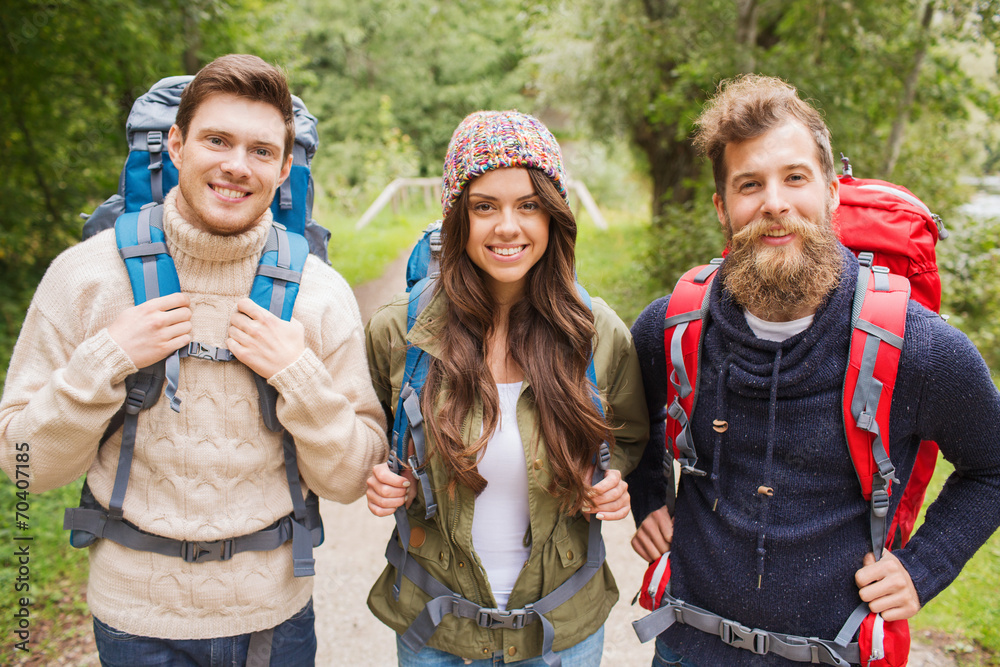 group of smiling friends with backpacks hiking