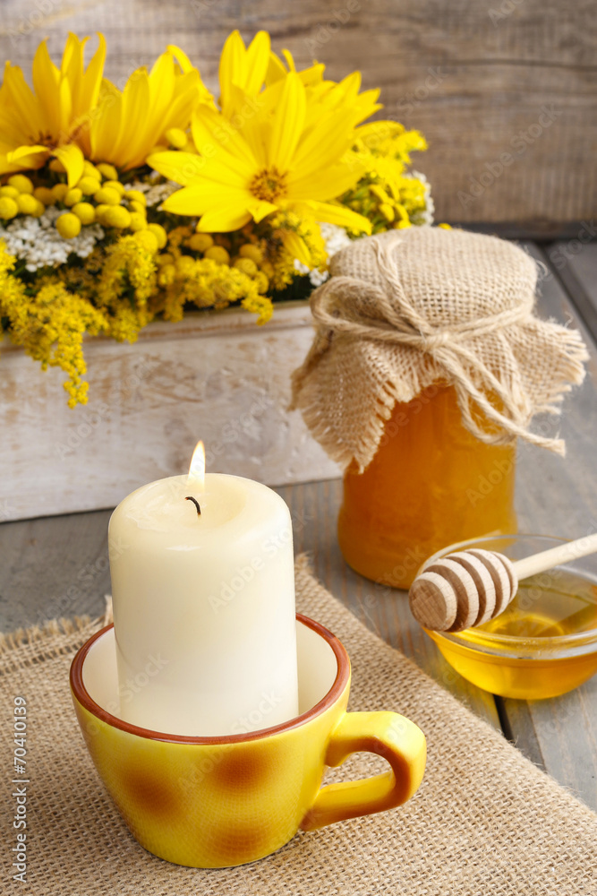 Jar of honey on wooden table, bouquet of sunflowers in the backg Jar of honey on wooden table, bouquet of sunflowers in the backg