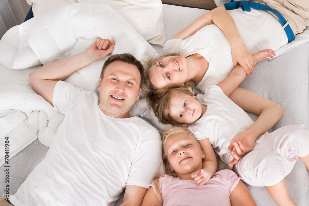 Young Family Lying Together In Bed